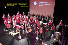 The Band receiving applause, on stage at the Roper Theatre, Bath, with the Devon & Somerset Corps of Drums in background.
